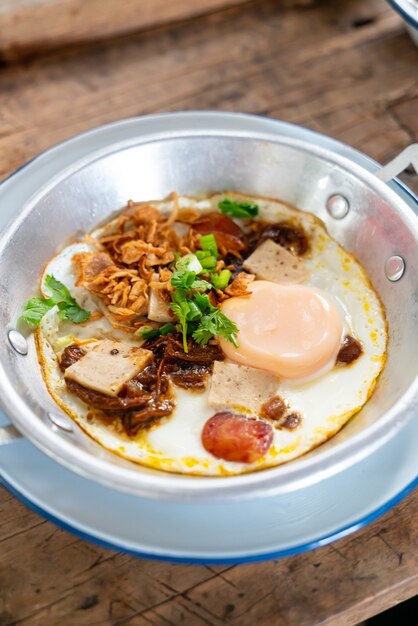 Pan Fried Egg Topping mit thailändischer Wurst auf Holztisch