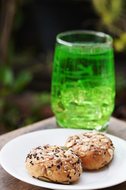 Foto pan de grano entero en un plato blanco con refresco verde en la mesa