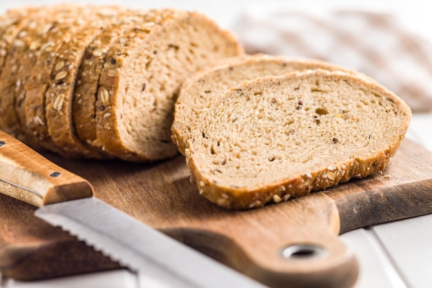 Pan de grano entero en rodajas Pastelería de grano completo sabrosa con semillas en la tabla de cortar