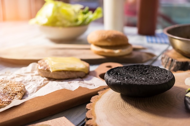 Pan de hamburguesa negro tableros de madera en la mesa de cocina nueva receta de hamburguesa