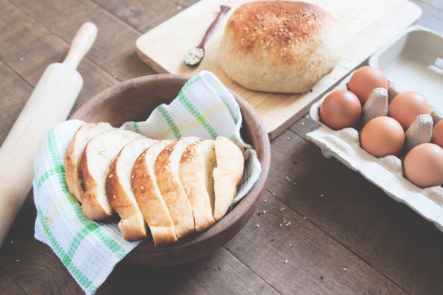 Pan hecho en casa listo para comer con pan de pan, huevos y herramientas de panadería sobre fondo de madera