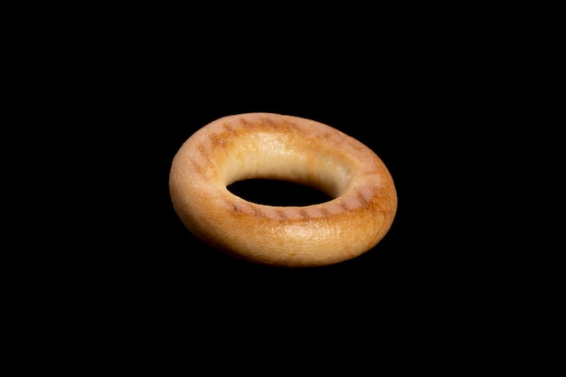 Pan de hojaldre de trigo en forma de anillo. bagel aislado sobre fondo negro. Foto de alta calidad