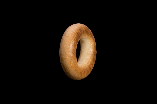 Pan de hojaldre de trigo en forma de anillo. bagel aislado sobre fondo negro. Foto de alta calidad