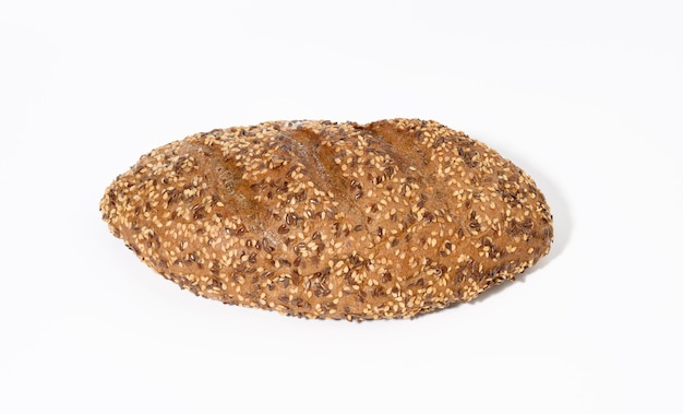 Pan horneado oblongo hecho de harina de centeno con semillas de sésamo blanco y semillas de lino sobre un fondo blanco.