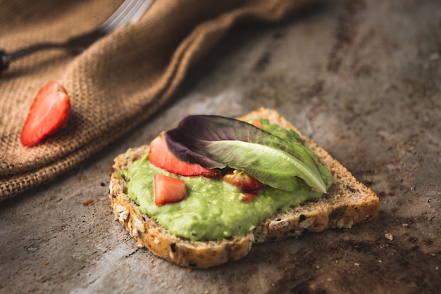 Pan integral de puré de aguacate y arándanos con fresa.