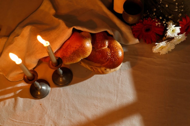 Pan jalá cubierto con una servilleta especial flores de velas en la mesa de la cocina Ritual tradicional judío de Shabat Shabbat Shalom