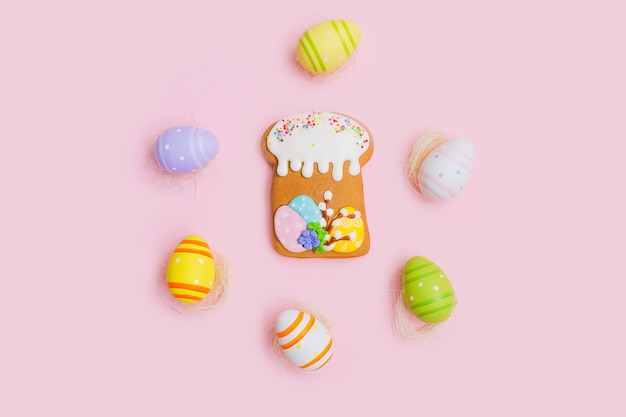 Pan de jengibre en forma de pastel y coloridos huevos de chocolate en un escritorio de madera blanca.