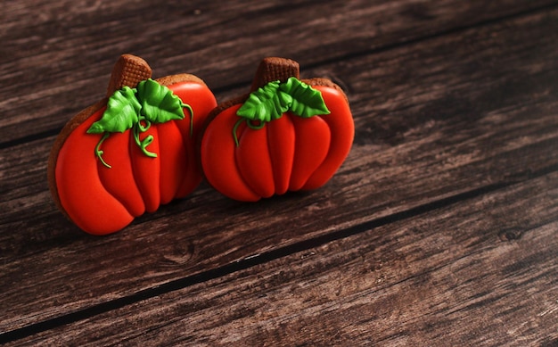 Pan de jengibre en un glaseado en forma de calabaza para Halloween en un primer plano de fondo de madera