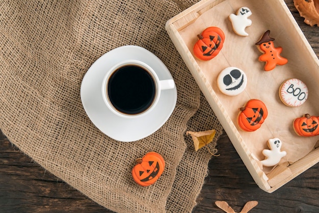 Pan de jengibre de Halloween en mesa de madera marrón y taza de café Galleta calabaza y fantasma Vista superior