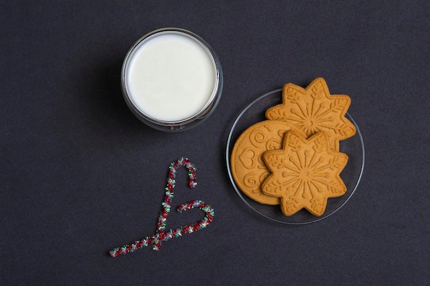 Pan de jengibre y leche para Santa. Composición navideña con galletas de jengibre y leche sobre un fondo negro, vista superior