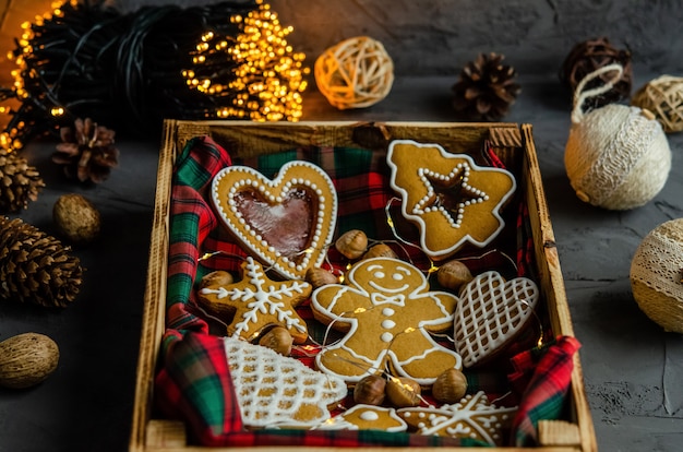 Pan de jengibre de Navidad con azúcar glas blanco pintado sobre un fondo oscuro.