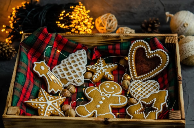 Pan de jengibre de Navidad con azúcar glas blanco pintado sobre un fondo oscuro.