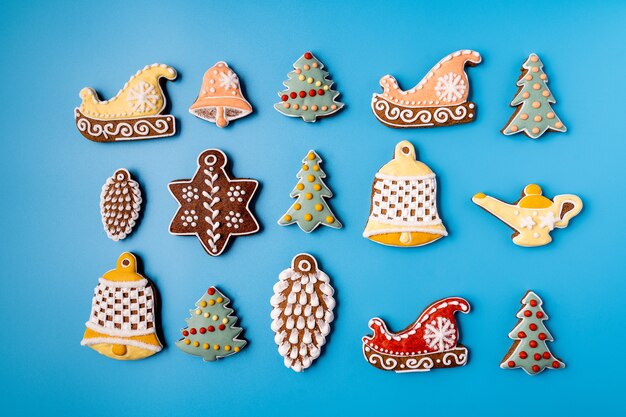 Pan de jengibre de Navidad sobre un fondo azul. Copo de nieve, abeto, estrella, trineo, conos, cono, estrella, forma de campana.