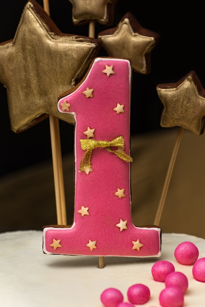 Pan de jengibre rosa con el número 1 en un pastel de vacaciones en una pared oscura. De cerca