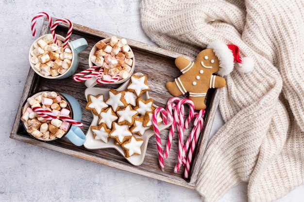 Pan de jengibre con taza de chocolate caliente y bastón de caramelo navideño.