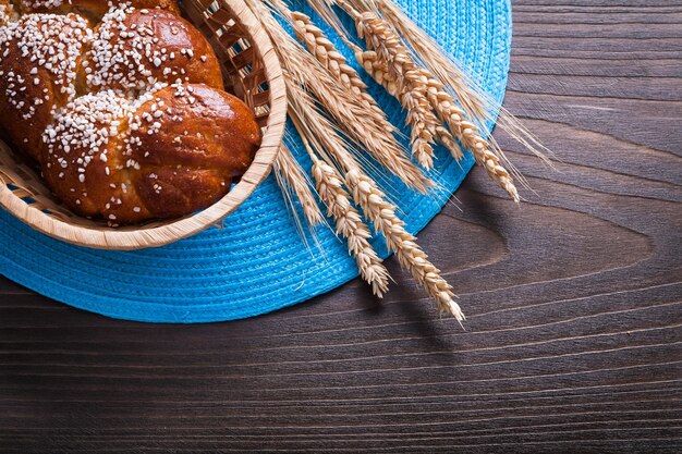 Pan largo en cesta de mimbre orejas de centeno de trigo con tela de barbas en concepto de comida y bebida de tablero vintage de madera