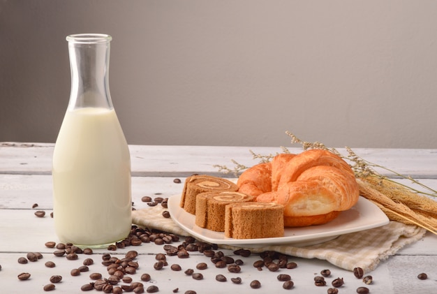 Pan y leche con café en grano para el desayuno en el fondo de madera