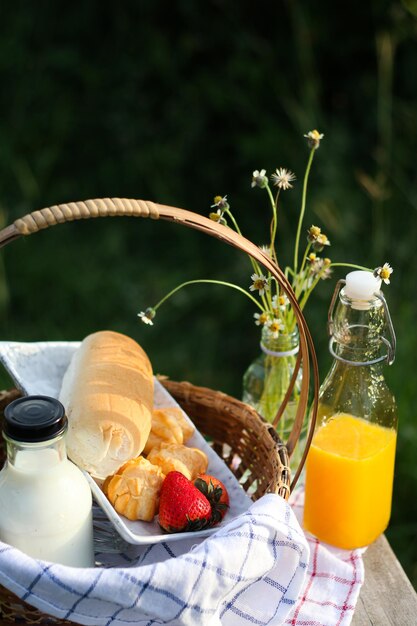 pan y leche en canasta con jugo de naranja en el fondo de la naturaleza