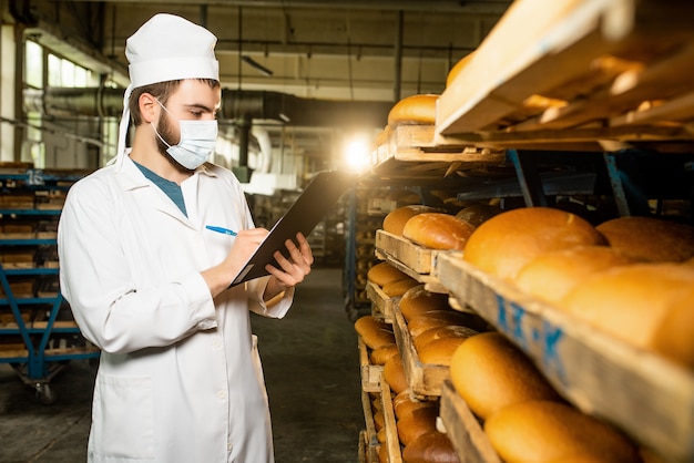 Un pan. Línea de producción de pan. Un hombre de uniforme. Control sanitario.