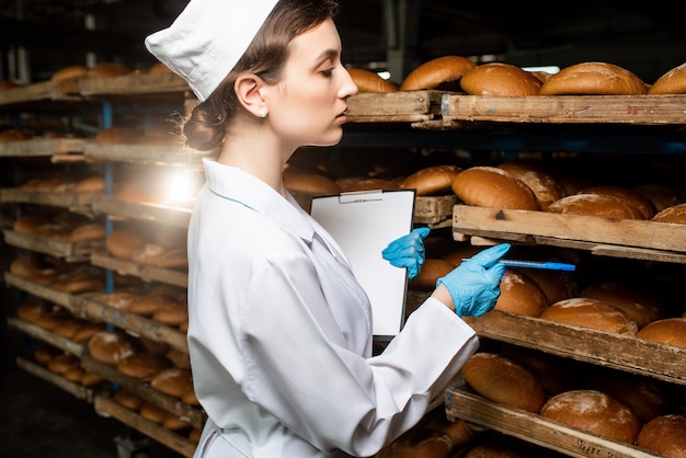 Foto un pan. línea de producción de pan. mujer en uniforme. control sanitario.