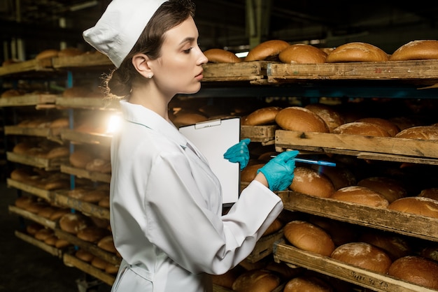 Foto un pan. línea de producción de pan. mujer en uniforme. control sanitario.