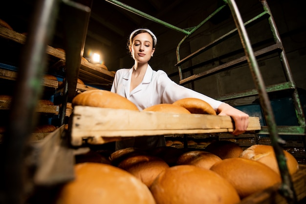 Un pan. Línea de producción de pan. Mujer en uniforme. Control sanitario.