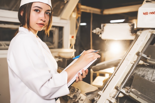 Un pan. Línea de producción de pan. Mujer en uniforme. Control sanitario.