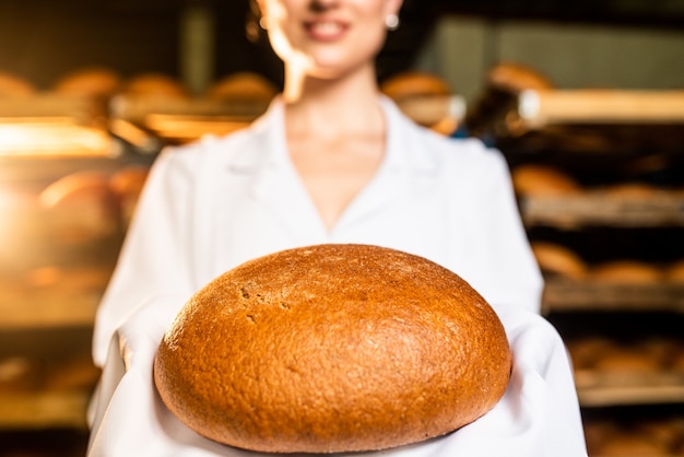 Foto un pan. línea de producción de pan. pan en la mano de la mujer.