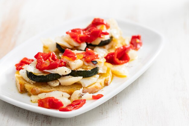 Pan de maíz con bacalao y calabacín en plato blanco