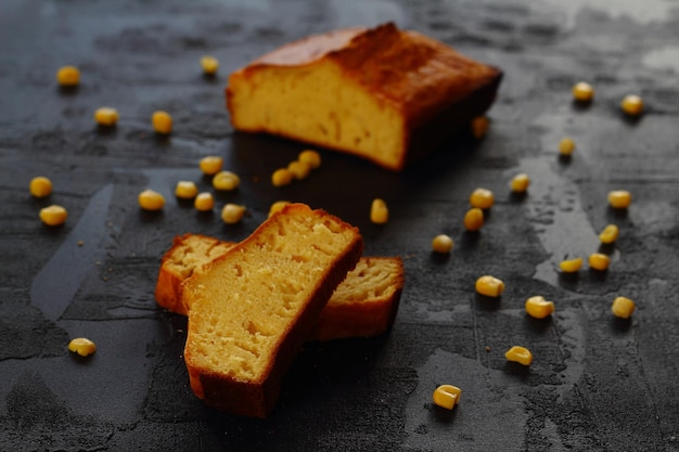 Pan de maíz con cuchillo sobre fondo negro con maíz fresco