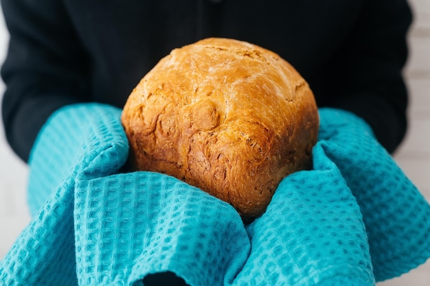 Pan de maíz recién horneado en una toalla de gofre azul en las manos del panadero