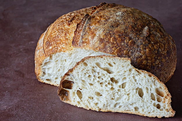 Pan de masa fermentada casero fresco con harina de grano entero sobre un fondo marrón. Comida sana.