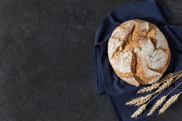 Pan de masa fermentada con corteza crujiente sobre fondo negro vista superior Productos de panadería orgánicos saludables