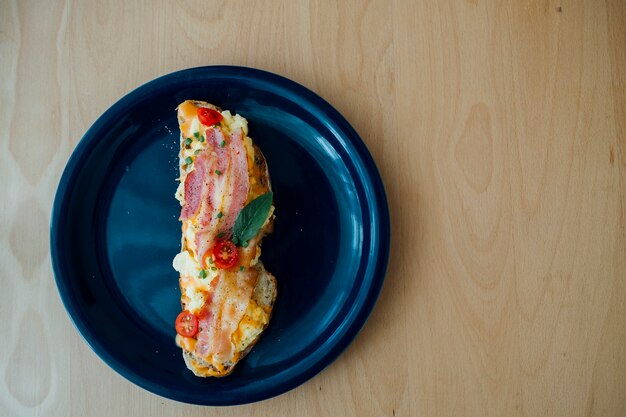 Foto pan de masa fermentada cubierto con tocino y huevos rotos