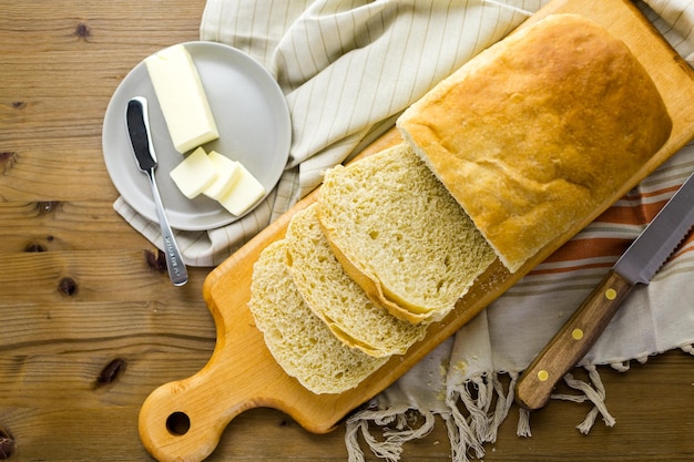 Foto pan de masa fermentada recién horneado cortado en rodajas sobre una tabla de cortar.