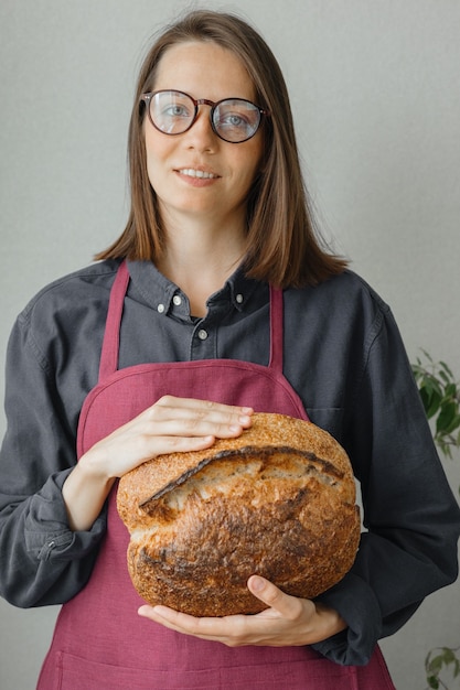 Pan de masa madre sin levadura una hermosa mujer europea panadero tiene pan en sus manos