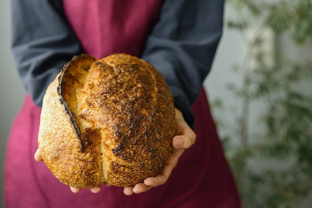 Pan de masa madre sin levadura una hermosa mujer europea panadero tiene pan en sus manos