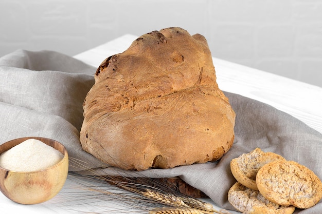 El pan de Matera Pane di Matera en servilleta de lino sobre fondo de madera blanca pan de masa fermentada típico del sur de Italia