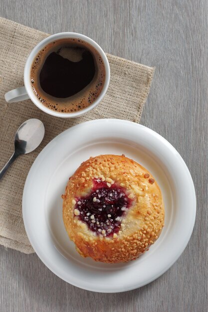 Pan con mermelada y una taza de café en la mesa vista de cerca de arriba