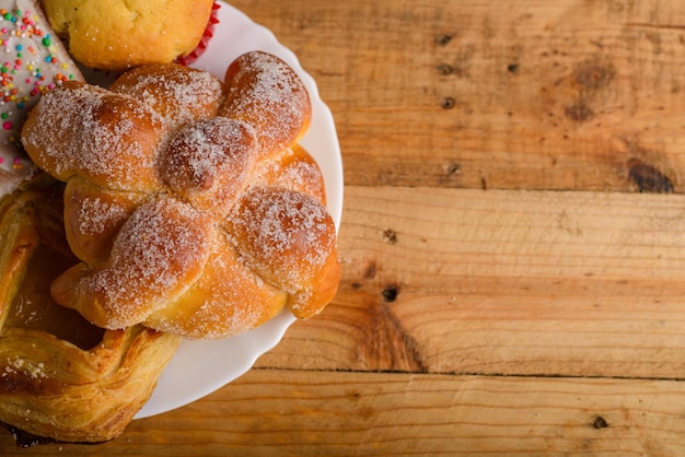 Pan de muerto y otros panes dulces en una mesa de madera Postre típico mexicano