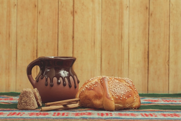 Pan de muerto y taza de chocolate sobre una mesa con mantel tpico mexicano