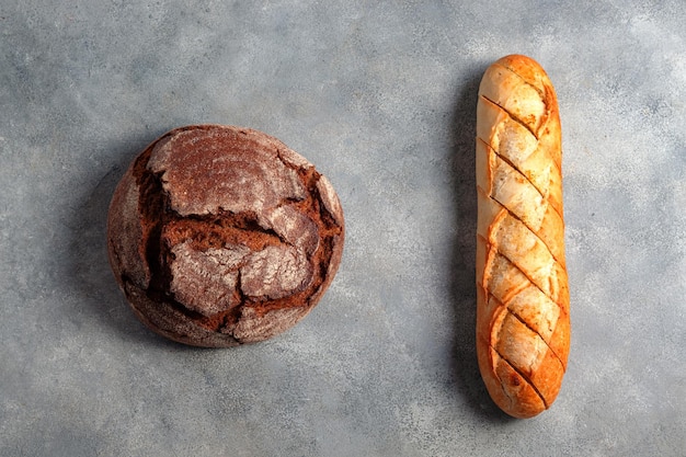 Pan oscuro artesanal sin levadura con baguette de pan de ajo en rodajas tostadas servida en concepto de panadería de fondo de piedra gris