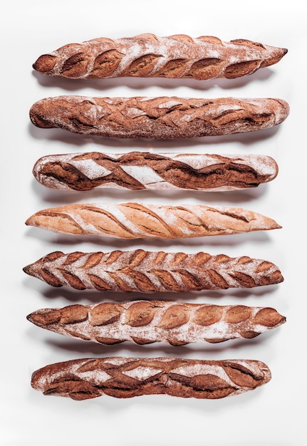 Pan de panadería, hogazas de pan crujientes rústicas frescas y baguette sobre fondo blanco.