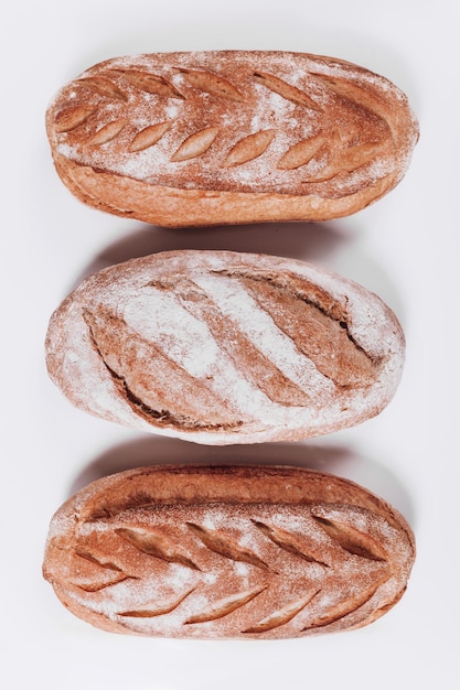 Pan de panadería, hogazas de pan crujientes rústicas frescas y baguette sobre fondo blanco.