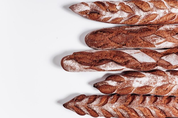 Pan de panadería, hogazas de pan crujientes rústicas frescas y baguette sobre fondo blanco.