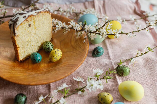 Pan de Pascua casero y huevos de Pascua teñidos naturales con flores de primavera en un plato de madera sobre una mesa rústica Comida tradicional de Pascua Feliz Pascua La mitad del pastel de Pascua horneado