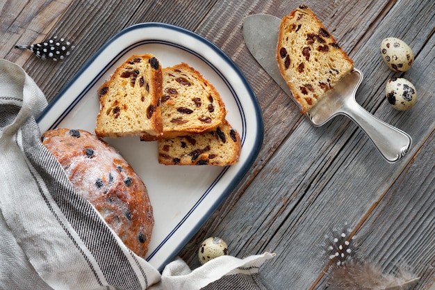 Pan de Pascua (Osterbrot en alemán). Vista superior del pan tradicional afrutado en madera rústica con hojas frescas y huevos de codorniz