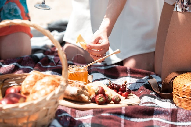 Pan de picnic, canasta de croissant con frutas sobre tela con luz solar brillante. Croissant, miel, fresa. Opción saludable para pasar tiempo en la naturaleza en un día de verano. Alimentos, nutrición, alimentación saludable.