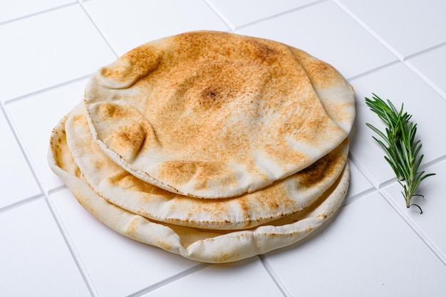Pan de pita recién horneado sobre fondo de mesa de baldosas cuadradas de cerámica blanca