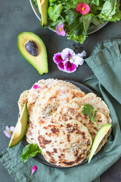 Pan plano chapati o roti con mezcla de ensalada verde, aguacate y brotes Pan plano indio recién horneado